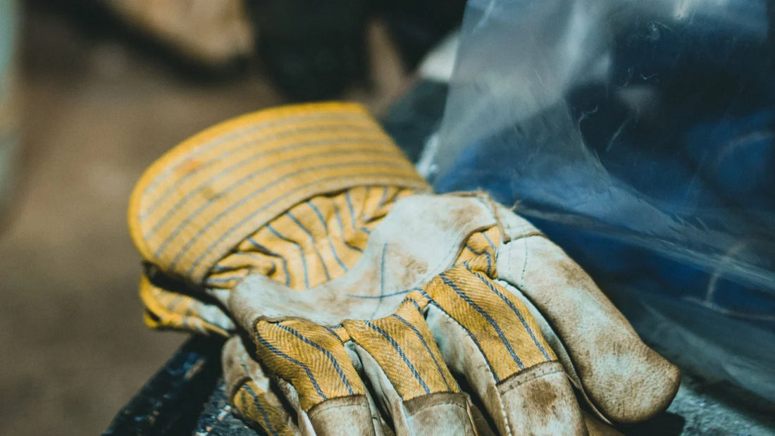 Worn leather work gloves resting on a workshop bench