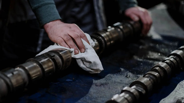 Wiping a cleaned engine camshaft in a workshop
