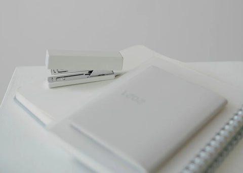 Notebooks, stapler and office supplies on a white desk