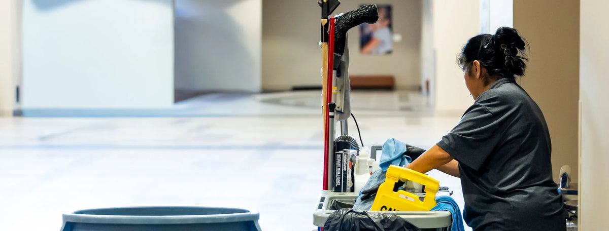 Janitorial staff pushing a cleaning cart down a hallway